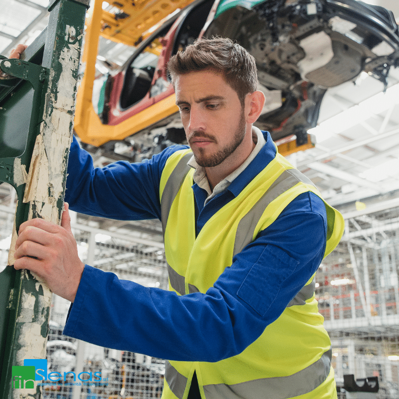 Perché conviene il noleggio operativo di beni strumentali Operaio in giubbotto ad alta visibilità lavora su una linea di montaggio industriale in un impianto produttivo