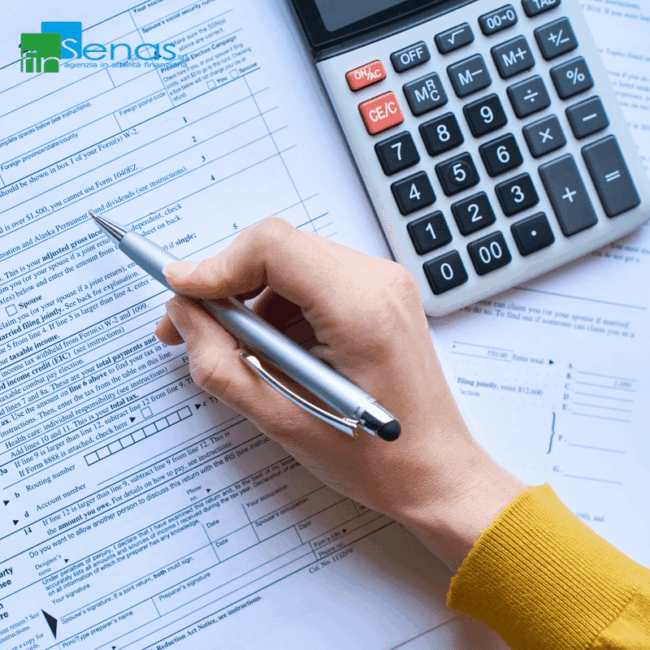 Mano che compila un modulo fiscale con calcolatrice accanto, simbolo di dichiarazione dei redditi.