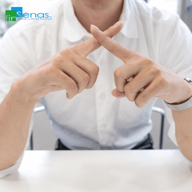 Uomo con camicia bianca incrocia le dita a forma di X davanti a sé, gesto che simboleggia un rifiuto