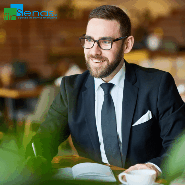 Professionista seduto al tavolo in un ambiente moderno, sorridente e pronto a discutere su un argomento importante, simbolo di consulenza finanziaria