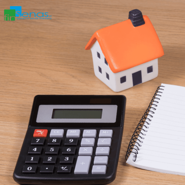 Calcolatrice, blocco note e modellino di casa con tetto arancione su un tavolo in legno