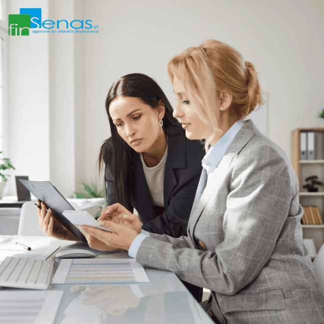 Regime de minimis 2025 come funziona davvero e cosa cambia per le PMI Due donne, in abiti professionali, discutono e consultano documenti su un tavolo da lavoro, mentre una di loro tiene in mano un tablet. Il logo di FinSenas è visibile nell’angolo in alto a sinistra.