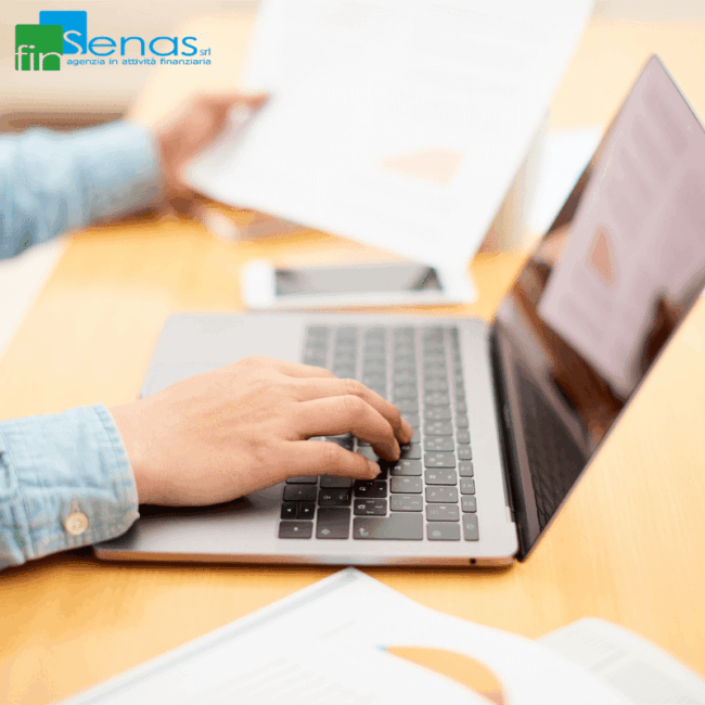 ZES Unica 2025 come inviare la comunicazione integrativa senza perdere il credito d’imposta Persona che lavora al computer esaminando documenti fiscali, con la mano sulla tastiera e fogli con grafici sul tavolo.