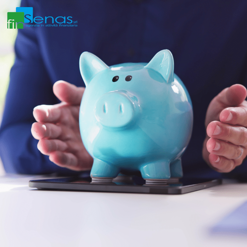 Come gestire al meglio il risparmio e gli investimenti guida pratica Salvadanaio azzurro poggiato su uno smartphone, protetto dalle mani di una persona, simbolo di gestione consapevole del risparmio e degli investimenti.
