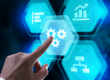 Mano che interagisce con icone digitali di ingranaggi e grafici, simbolo degli investimenti tecnologici e della gestione aziendale.