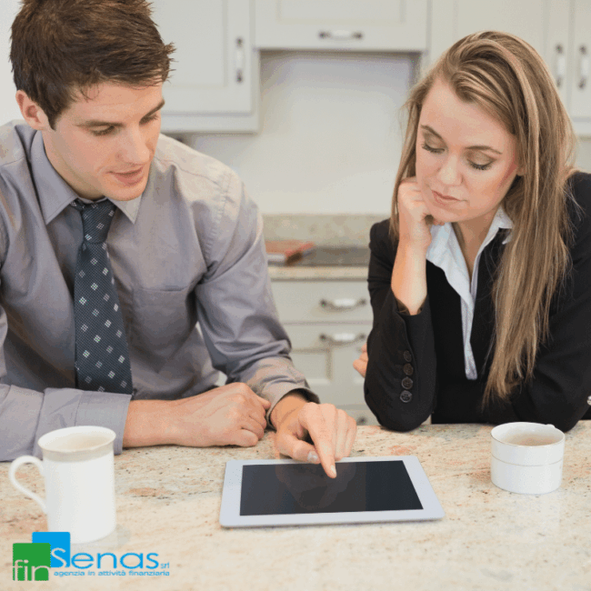 Due persone analizzano insieme un tablet su un tavolo, valutando soluzioni finanziarie come il consolidamento dei debiti.