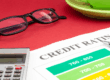Carta con il termine "Credit Rating", calcolatrice, occhiali e una tazza, simbolo di valutazione del rischio aziendale.