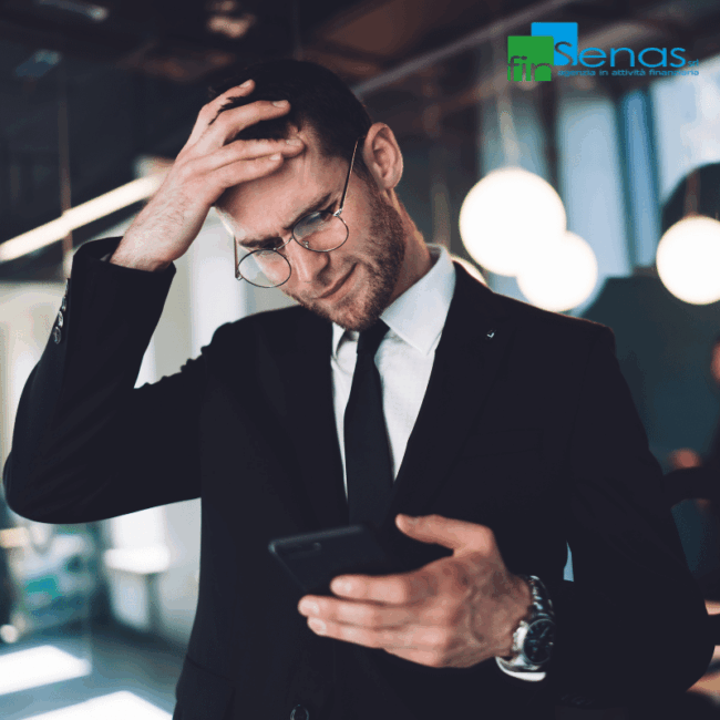 8 Motivi più comuni per cui un prestito viene rifiutato e come evitarlo Uomo in giacca guarda il telefono con espressione preoccupata, simbolo del rifiuto di un prestito.