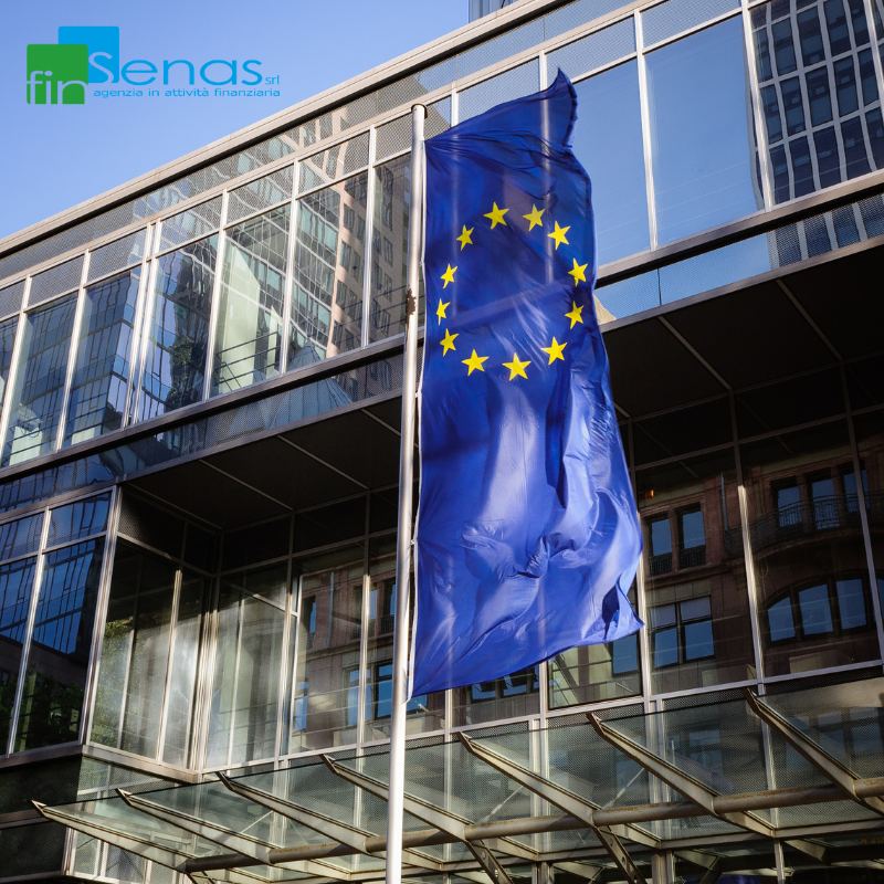 BCE rialza i tassi inflazione in aumento e impatto su famiglie e imprese Bandiera dell’Unione Europea sventolante davanti a un edificio moderno con facciata in vetro, immagine rappresentativa della BCE e delle politiche monetarie.