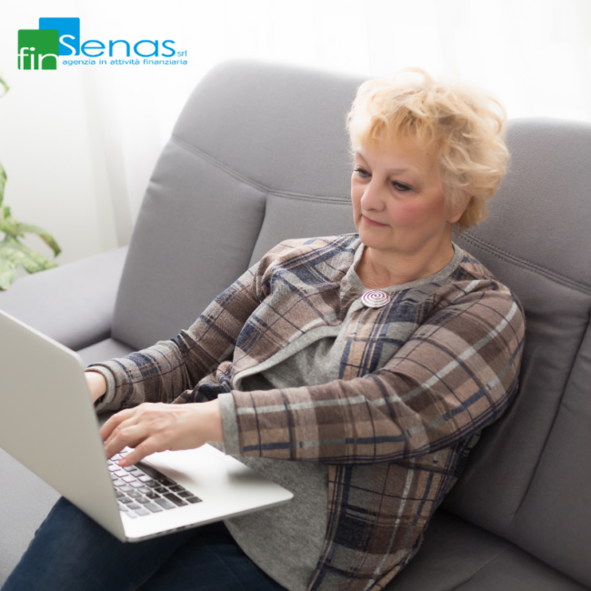 Pensione di reversibilità quando l’INPS può diminuirla o sospenderla Donna anziana seduta sul divano mentre utilizza un computer portatile, immagine rappresentativa della pensione di reversibilità e delle verifiche INPS.