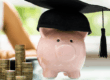 Salvadanaio a forma di maialino con cappello da laurea accanto a monete, rappresentando l’importanza dell’educazione finanziaria e della gestione consapevole del denaro.