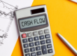 Calcolatrice con la scritta “Cash Flow” accanto a documenti finanziari e grafici aziendali.