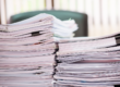 Pile di documenti cartacei e pratiche amministrative su una scrivania, simbolo della gestione delle procedure fiscali.
