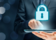 Persona in abito professionale utilizza un tablet con un simbolo di lucchetto digitale che rappresenta la sicurezza informatica.