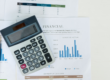 Calcolatrice appoggiata su documenti finanziari con grafici e tabelle, rappresentativa della valutazione economica di un finanziamento aziendale.